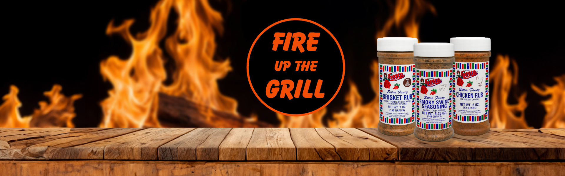 Fiesta Spices home page Fire up the grill wooden table with three jars of rubs with open flames in background