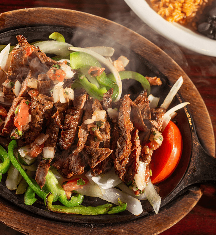 Southwest Skillet Fajitas with That Just-Grilled Flavor Steaming beef fajitas with onions and bell peppers served in a cast iron skillet, seasoned with Bolner’s Fiesta Brand Southwest Style Fajita Seasoning.