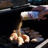 Fiesta Brand Wing Tips seasoning being sprinkled over raw chicken wings on a charcoal grill.